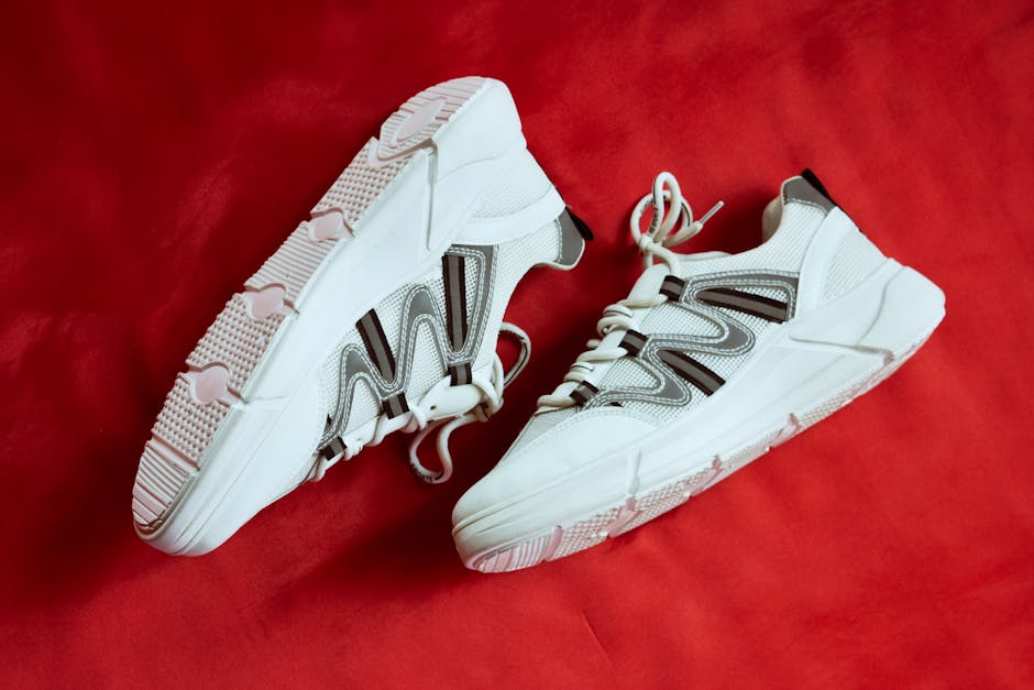 Stylish white sneakers showcased against a vibrant red backdrop, emphasizing contemporary design.