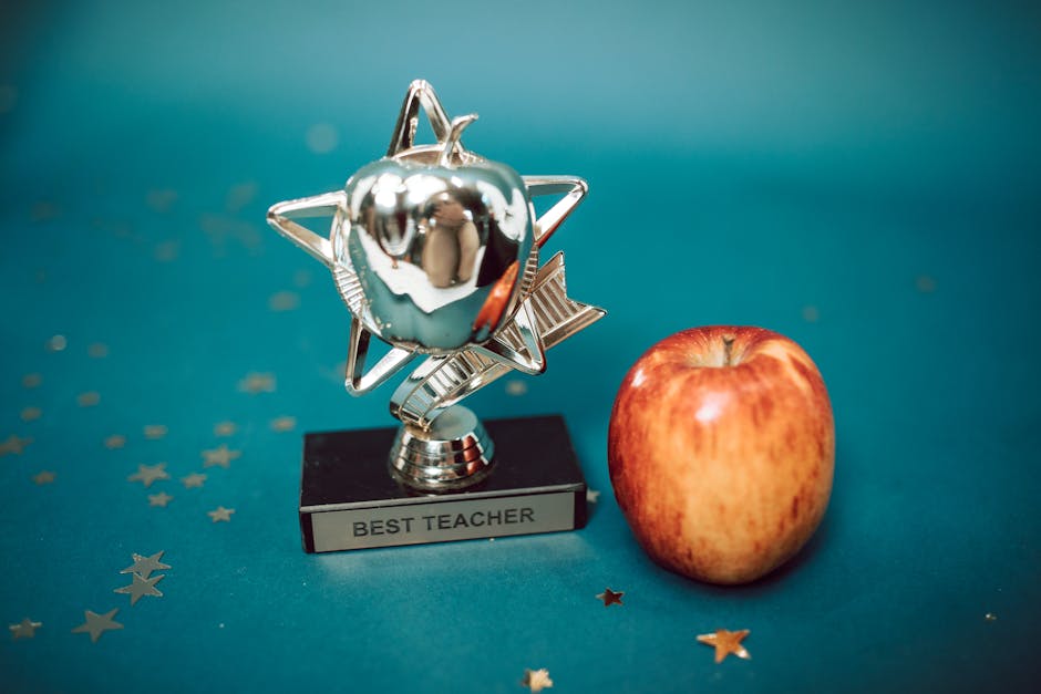 Silver star-shaped trophy with apple on a blue background for teacher appreciation.
