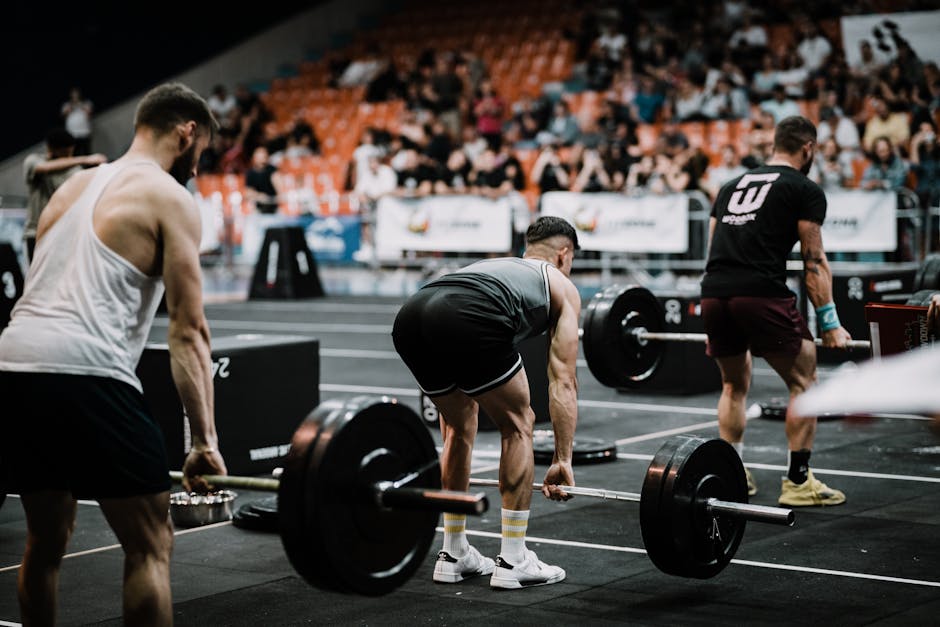 A group of athletes performing deadlifts during a competitive weightlifting event indoors.
