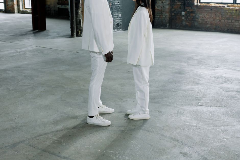 Two individuals face each other in white clothing, symbolizing equality in an industrial setting.