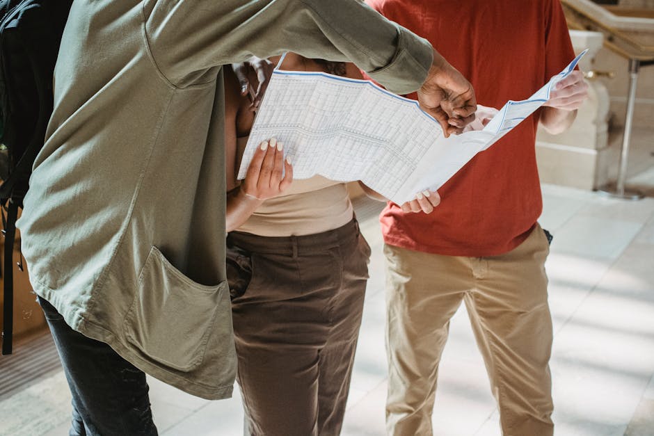 Crop unrecognizable African American male tourist pointing at map while standing in corridor with friends