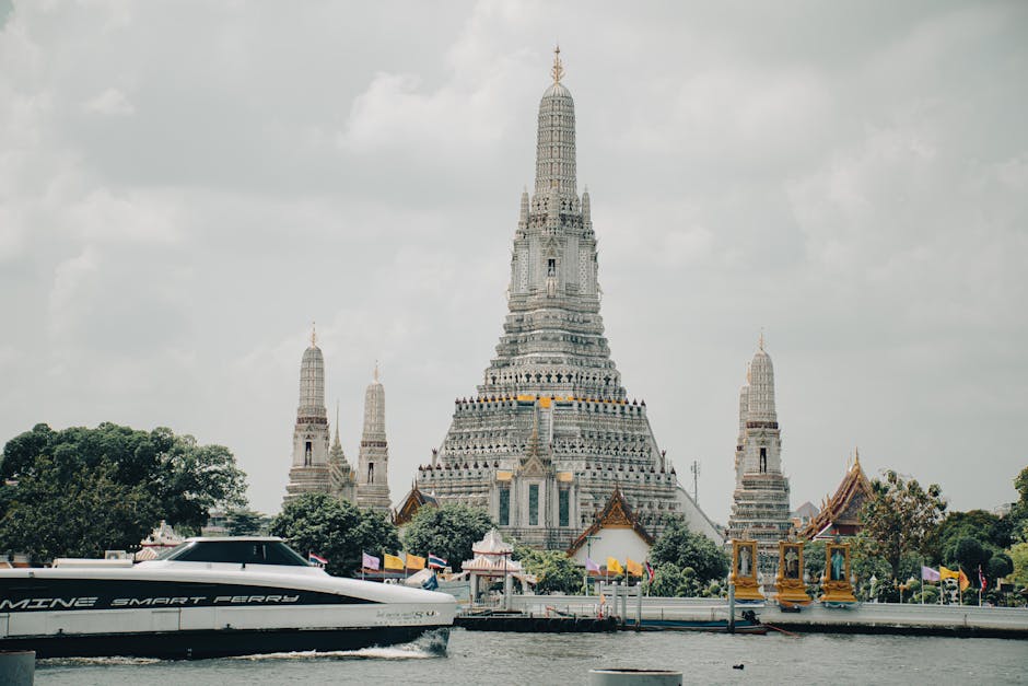 Stunning view of Wat Arun temple and Chao Phraya River in Bangkok, Thailand with a ferry boat.