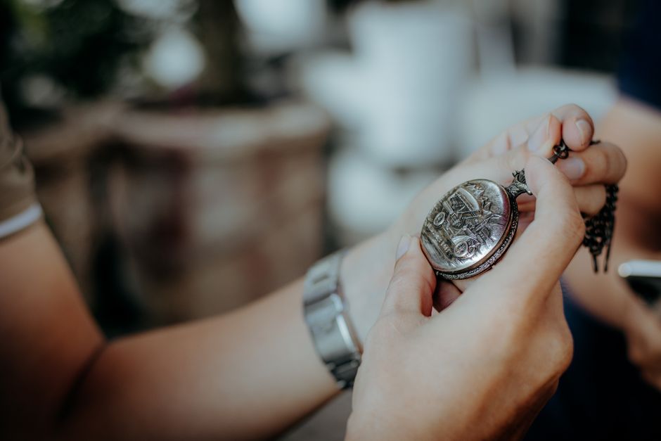 Intricate antique pocket watch held in hand. Detailed close-up showing vintage timepiece.