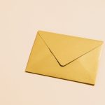 A sleek gold envelope placed on a vibrant yellow background, perfect for postal themes.