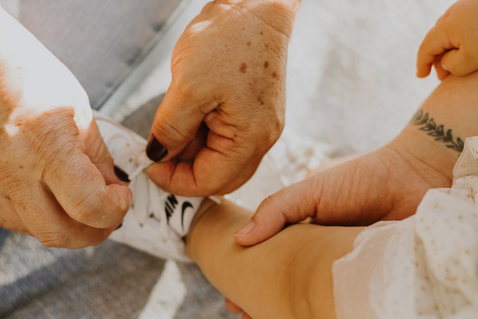 An elderly woman helps tie a baby's Nike shoe, highlighting care and intergenerational bonding.
