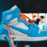 Vibrant University Blue Off-White Nike Jordan 1 sneakers held against a blurred background.