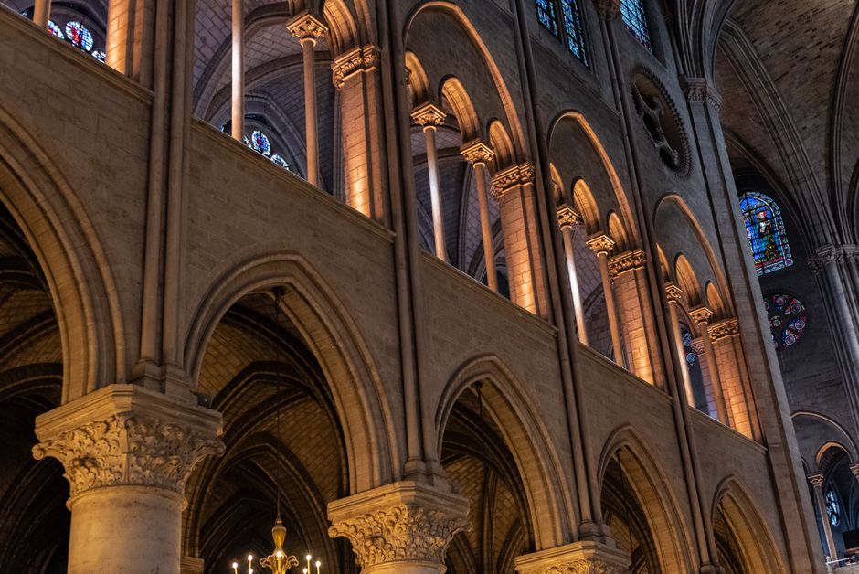 Intricate gothic arches and stained glass in a historic French church interior.