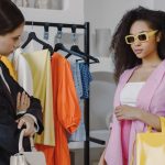 Two women exploring fashion choices with a stylist indoors.